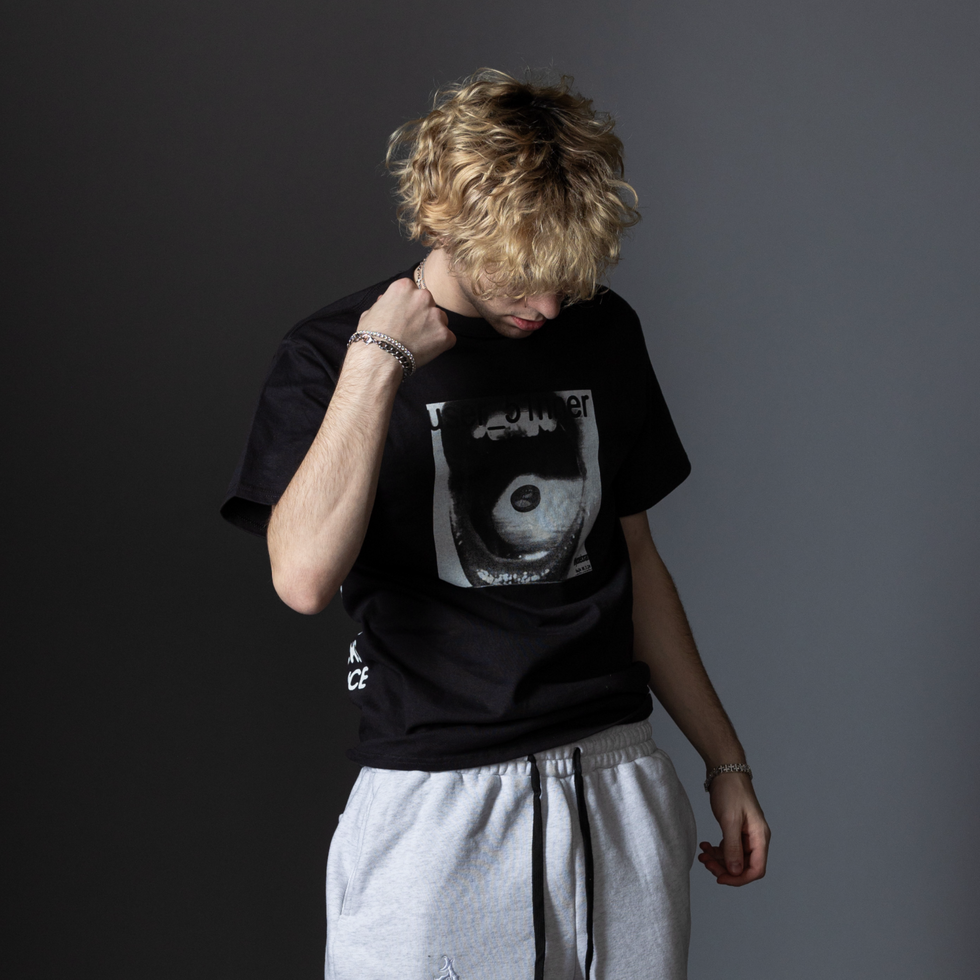 51nner tee in black, model photo, on gray backdrop. Gray fiftyonebrand sweatpants are seen slightly cut off. 