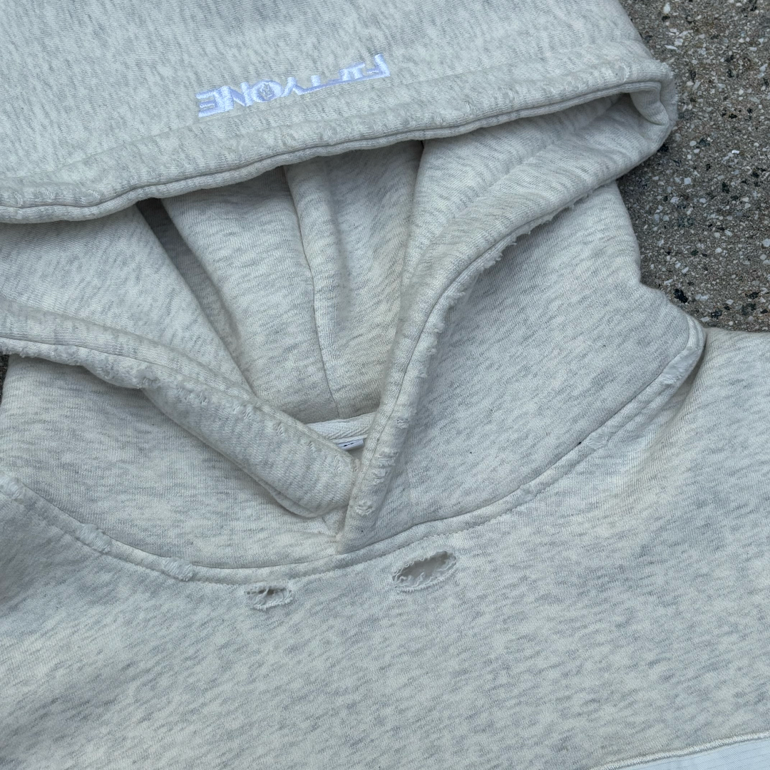 Gray hoodie with upside down 'FIFTYONE' branding on a concrete surface